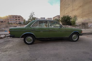 Yeşil bir Mercedes 'e yakın çekim. Yolda 250' lik park edilmiş.