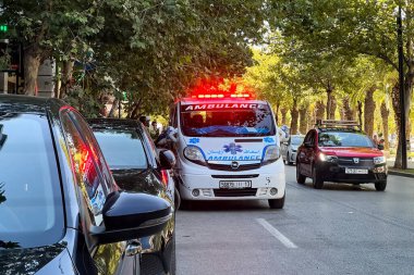 Ambulans aracı yol kenarına park etmiş, acil durum ışıkları yanıp sönüyor.