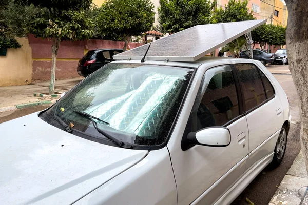 Yol kenarına park etmiş, üzerinde güneş panelleri olan küçük bir araba.