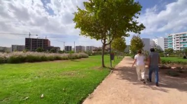 Şehir parkında birlikte yürüyen yaşlı bir çift.