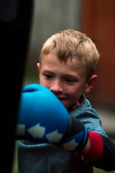 Boy Punches Punching Bag Blue Gloves Yard — Stockfoto
