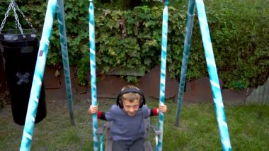 a boy listens to music in headphones near in the yard