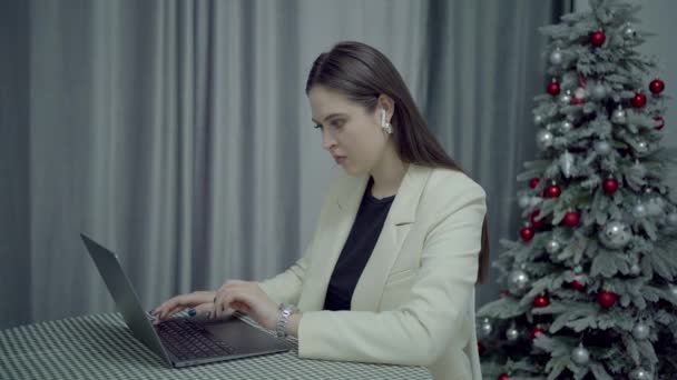 Mujer de negocios que trabaja con el ordenador portátil en casa, árbol de año nuevo en el fondo — Vídeos de Stock