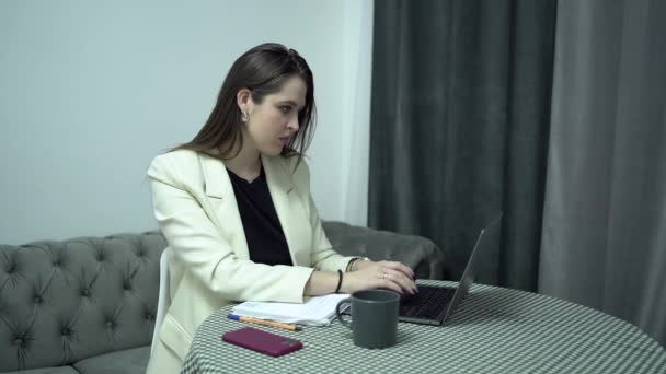 Бізнес-леді з ноутбуком роблять нотатки в газетах, домашній офіс — стокове відео