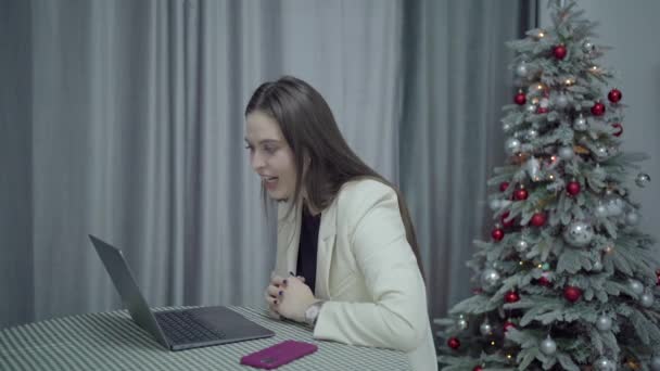 Lycklig kvinna pratar vid videosamtal, nyårsträd hemma — Stockvideo