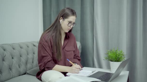 Frau mit Brille und Laptop machen sich Notizen in Zeitungen, Wohnungseinrichtung — Stockvideo