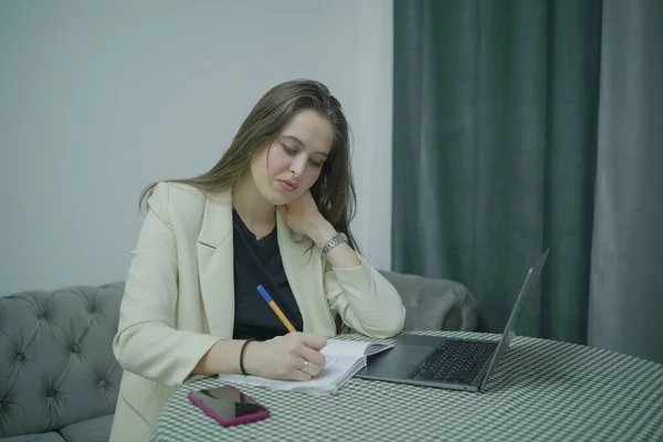 Bilgisayarlı iş kadını kağıtlara not alıyor, ev ofisine.