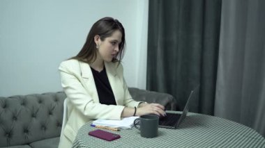 Bilgisayarlı iş kadını kağıtlara not alıyor, ev ofisine.