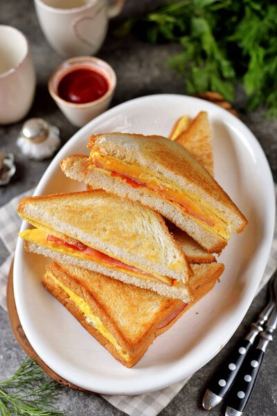 Sandwiches with egg, ham and toast cheese fried in a pan.