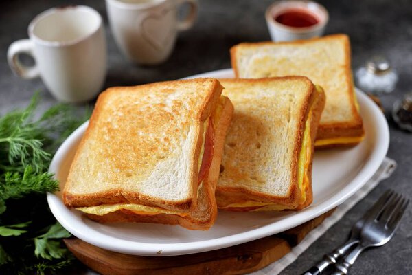 Sandwiches with egg, ham and toast cheese fried in a pan.