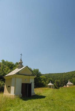 Güneşli bir yaz gününde, Polonya 'nın Kalwaria Paclawska kentinde tarlalar ve ormanlarla çevrili bir şapel.