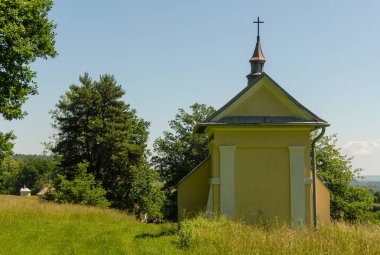 Güneşli bir yaz gününde, Polonya 'nın Kalwaria Paclawska kentinde tarlalar ve ormanlarla çevrili bir şapel.
