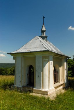 Güneşli bir yaz gününde, Polonya 'nın Kalwaria Paclawska kentinde tarlalar ve ormanlarla çevrili bir şapel.