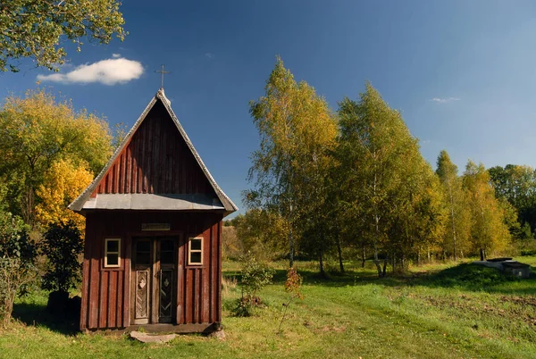 Lublin, Polonya - 30 Eylül 2012: Çayırlar ve tarlalar arasında ahşap bir şapel ve güneşli bir sonbahar günü