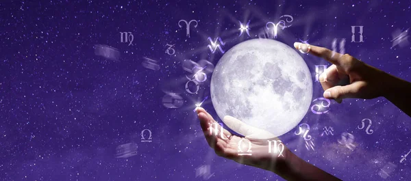 Astrological zodiac signs over the moon in hand. Knowledge of the stars in the sky. The power of the universe concept.