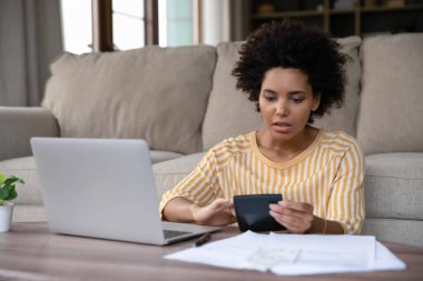 Harcamaları hesaplayan stresli Afrikalı genç bir kadın..