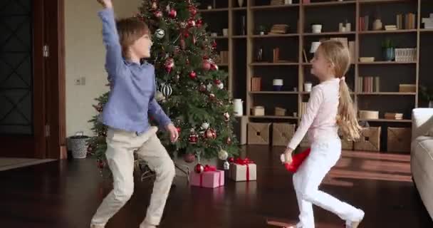 Nastoletni starszy brat młodsza siostra zabawy przez choinkę — Wideo stockowe