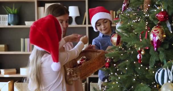 Joyeux jeune maman garniture arbre de Noël avec petit fils fille — Video