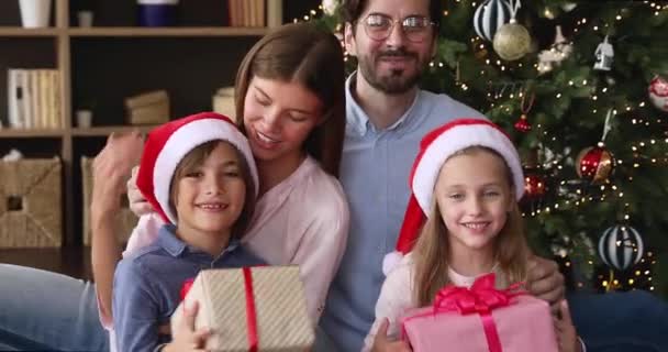 温馨的一家人坐在圣诞树下挥手捧着礼物 — 图库视频影像