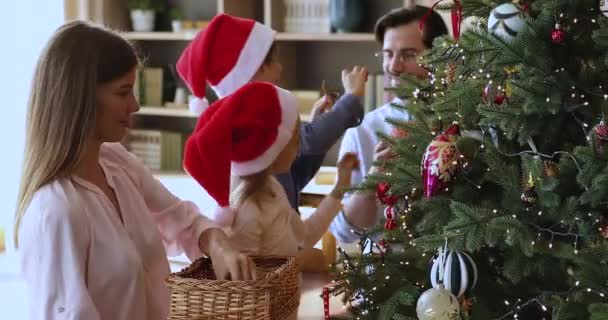 Μητέρα πατέρας προεφηβικά παιδιά απολαμβάνουν οικογενειακή παράδοση διακοσμούν χριστουγεννιάτικο δέντρο — Αρχείο Βίντεο