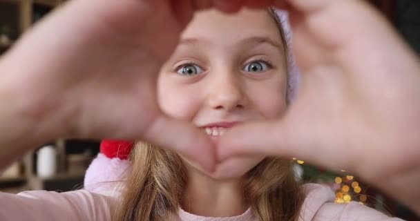 Ragazzina in tappo di Natale fare cuore dito prima della fotocamera — Video Stock