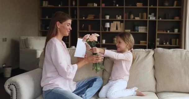 Liten flicka ger blommor vykort till mor på kvinnodagen — Stockvideo