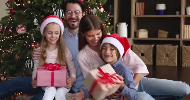 Pais crianças que encontram o Natal em casa sob o abeto decorado — Vídeo de Stock