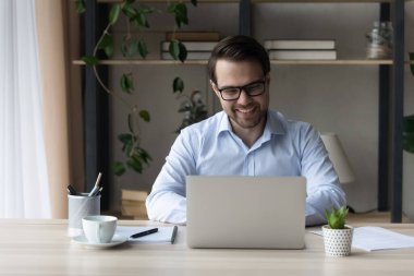 İnternette çalışan, gözlüklü, güler yüzlü iş adamı.