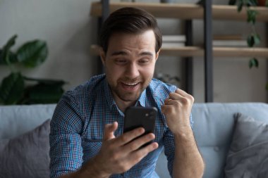 Kapatın neşeli adamı, başarıyı kutluyor, elinde akıllı telefon tutuyor.