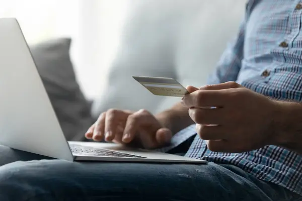 Close up man paying online by credit card, using laptop