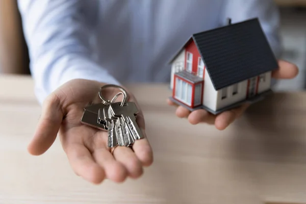 Crop close up uomo agente immobiliare in possesso di chiavi e modello di casa — Foto Stock