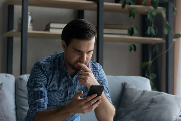 Ragionevole uomo serio toccare mento, guardando lo schermo dello smartphone — Foto Stock