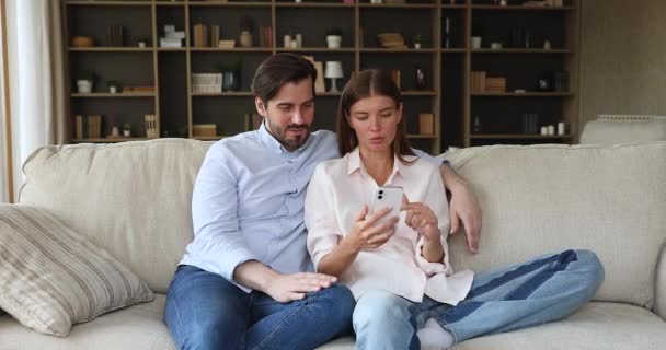 Молодая семейная пара наслаждается просмотром видео блога на мобильном телефоне — стоковое видео