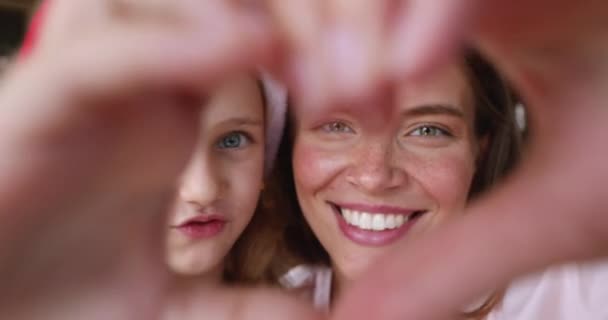 戴着圣诞礼帽的妈妈和女孩看穿了手指的心脏 — 图库视频影像