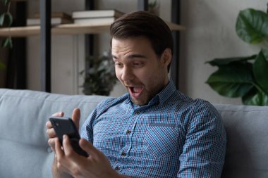 Kafasından vurunca sevinçle şaşıran adam akıllı telefon ekranına bakıyor.