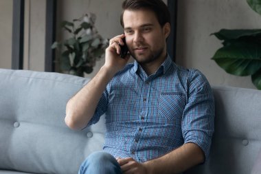 Gülümseyen adam telefonda konuşuyor, keyifli sohbetler ediyor.