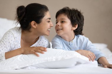 Genç mutlu Hintli anne yatakta oğluyla oynuyor..