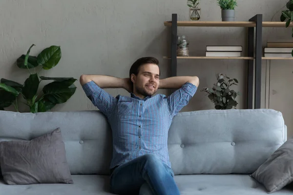 Uomo sorridente seduto rilassante sul divano accogliente, visualizzando il futuro — Foto Stock