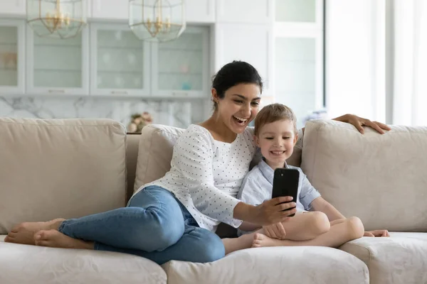Счастливые связи смешанной расы семьи с помощью мобильного телефона дома. — стоковое фото