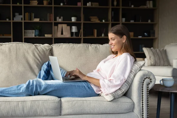 Happy dívka s notebookem relaxaci na gauči v obývacím pokoji — Stock fotografie