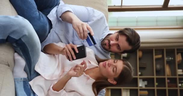Glad tusenåriga par gör betalning online med hjälp av telefon plastkort — Stockvideo