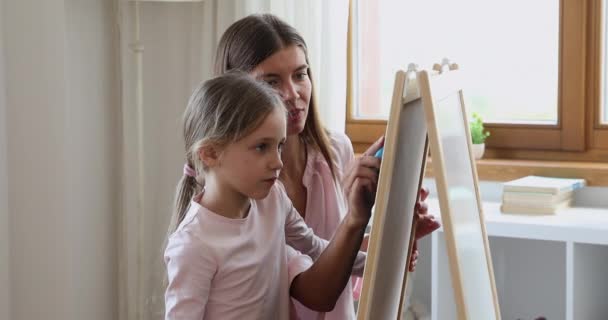 Mała córka naśladować mama rysować obraz na tablicy używając kredy — Wideo stockowe