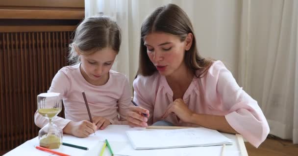 Millennial mam helpen kind schoolmeisje in het maken van schets op tijd — Stockvideo
