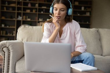 Büyük kulaklıklı ciddi milenyum öğrencisi kız evden ders çalışıyor.