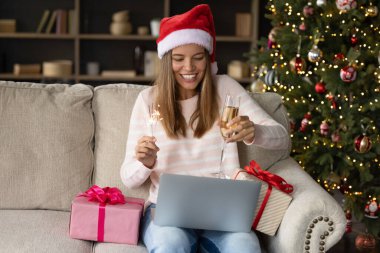 Noel Baba şapkalı mutlu kadın köpüklü şarap içiyor.