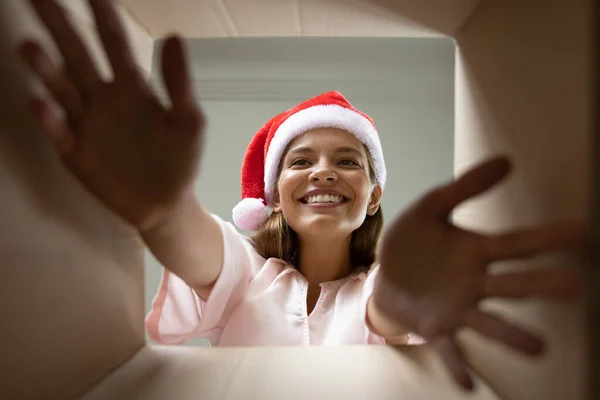 Ricevitore regalo di Natale eccitato a Santa cappello prendendo involucro regalo — Foto Stock