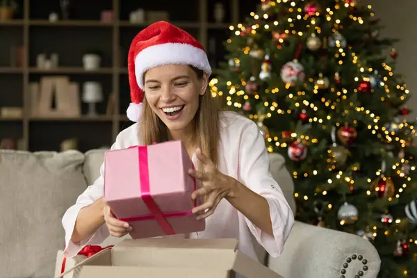 Šťastný vzrušený vánoční dívka v santa klobouk vybalování obdržel box — Stock fotografie