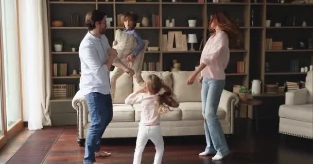 Активные родители с детьми-подростками танцуют в современной гостиной — стоковое видео
