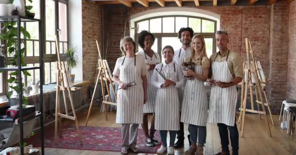 Grupo de personas diversas sosteniendo pinceles, posando en un estudio de arte — Vídeos de Stock