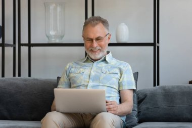 Bilgisayar kullanarak gözlüklü mutlu orta yaşlı bir adam..